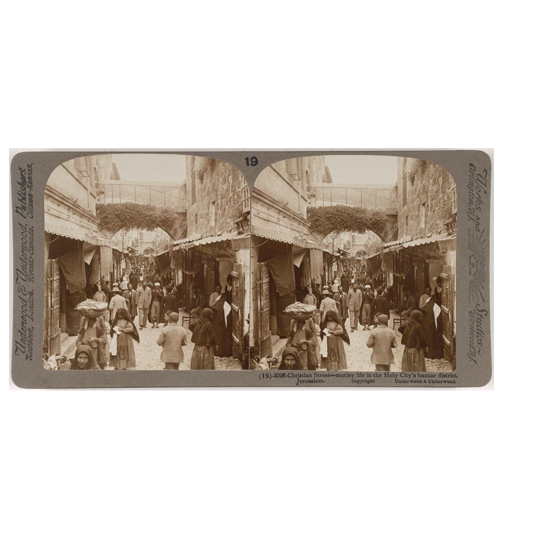 Christian Street, motley life in the Holy City's bazaar district, Jerusalem; a sepia photo of a crowded pedestrian street with shops on either side.